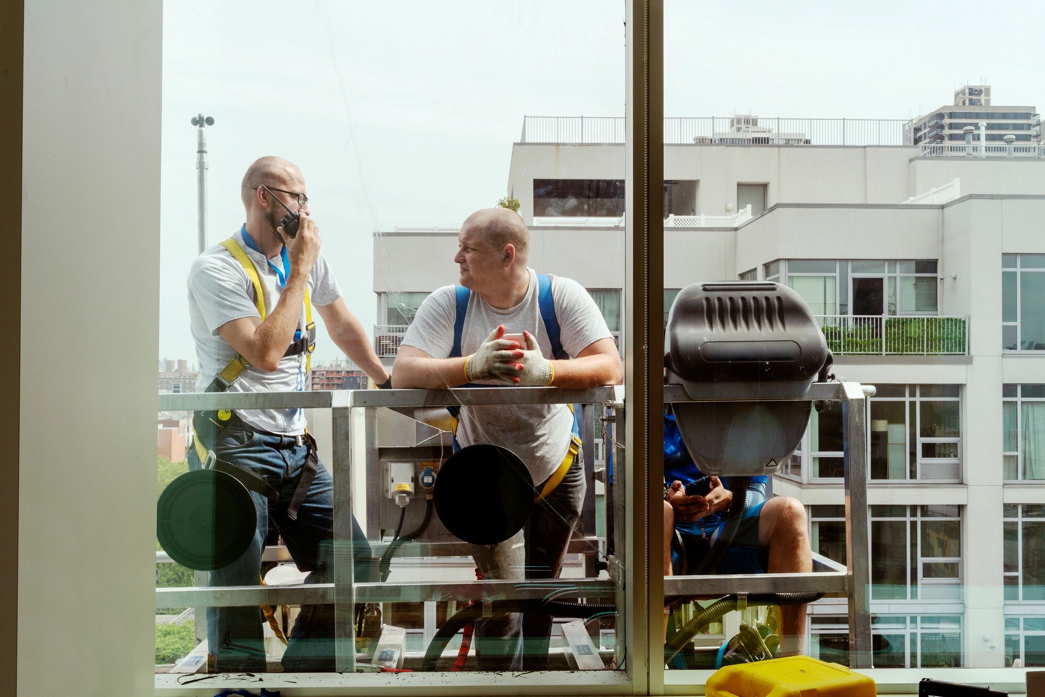Workers installing glass panel on building exterior